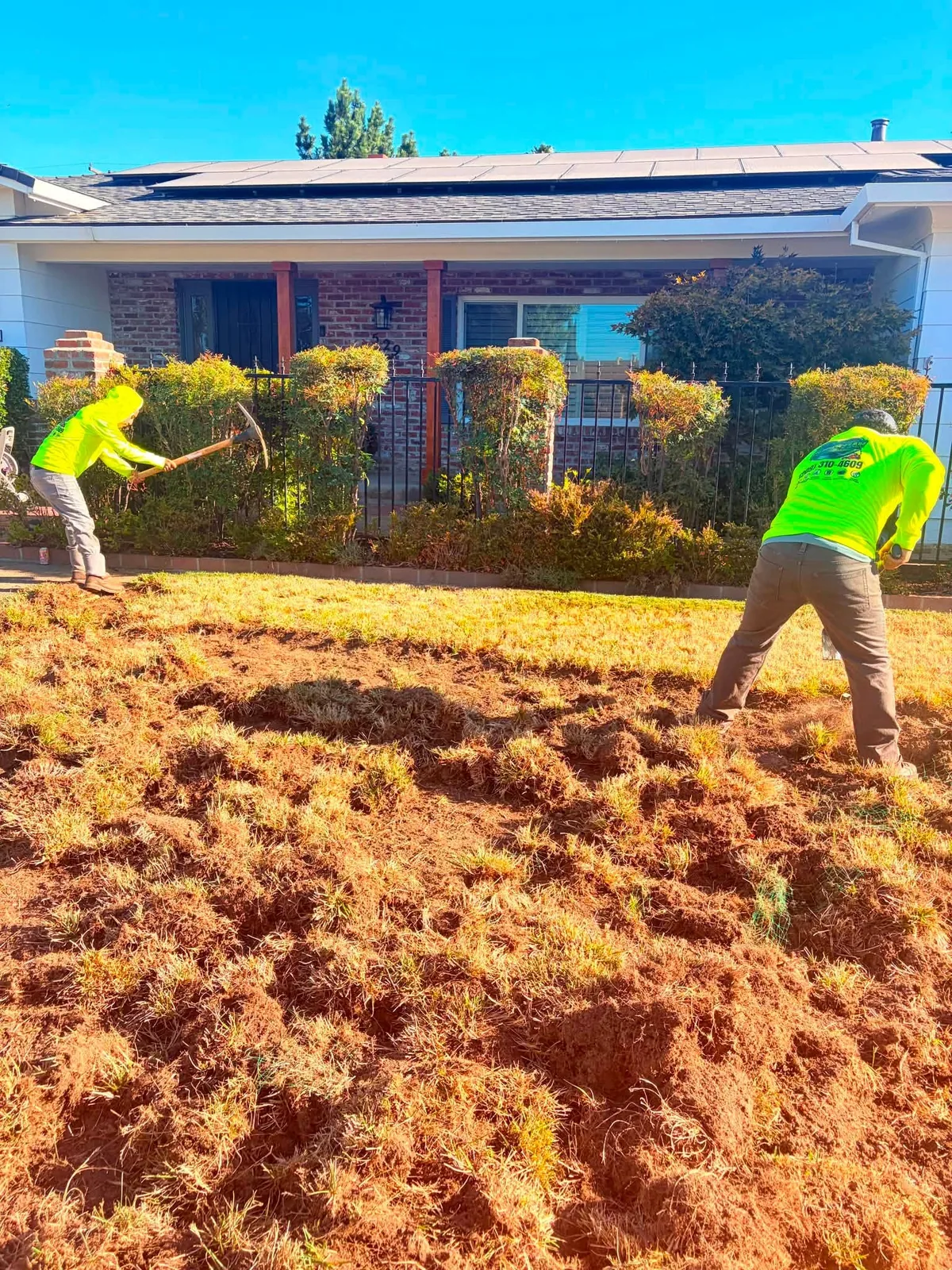 Dos trabajadores preparando el suelo de un jardín